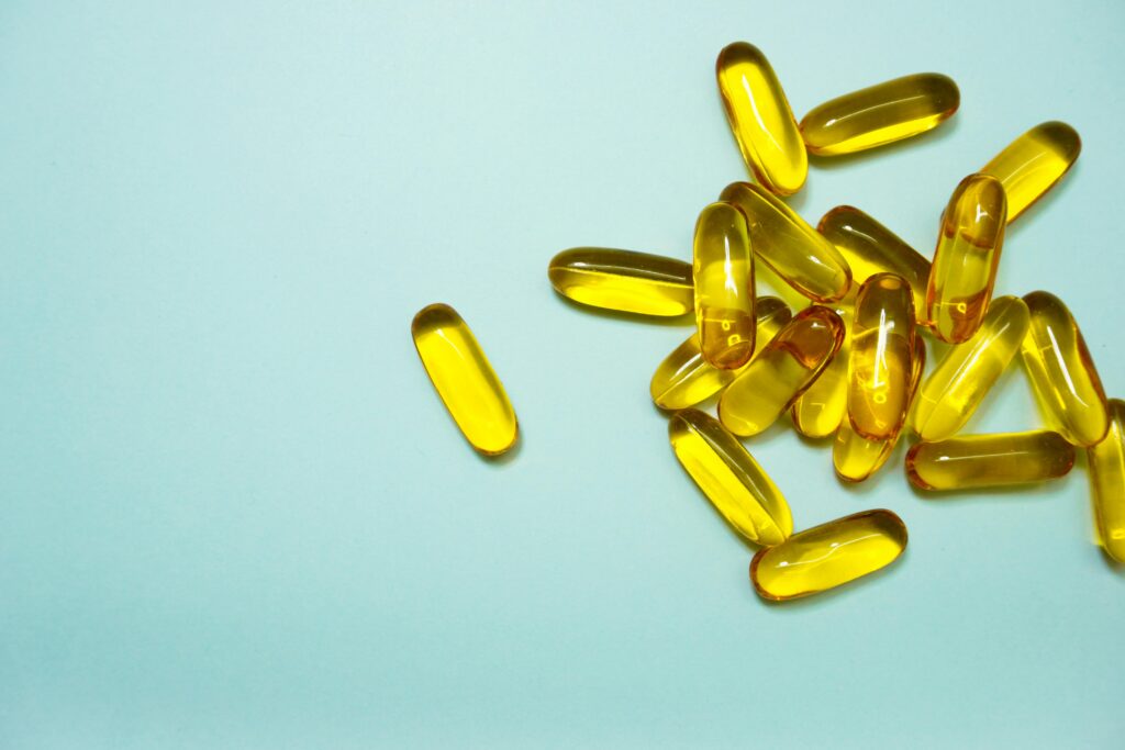 A collection of omega-3 capsules on a light blue surface, ideal for health and supplement themes.